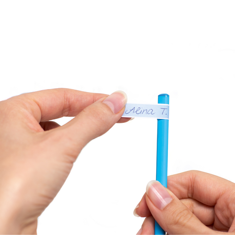 Eine Hand hält einen blauen Stift, während die andere Hand ein Stück Papier mit einem Namen darauf festhält.