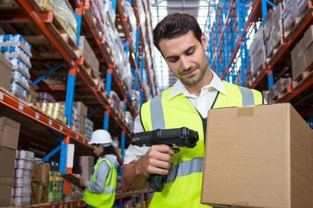 Logistics employee scanning a shipping label on a box in the warehouse, landscape orientation.