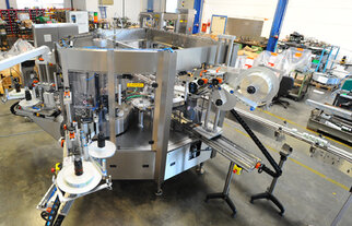 A complex packaging machine with multiple conveyor belts and labeling stations in a production environment.