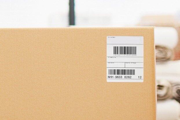 HERMA shipping labels and transport labels on cartons in the logistics sector, landscape format.