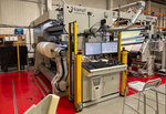 A large machinery system for processing materials, equipped with a control panel and monitors, in an industrial setting.