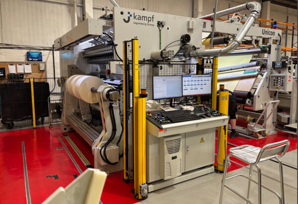 A large machinery system for processing materials, equipped with a control panel and monitors, in an industrial setting.