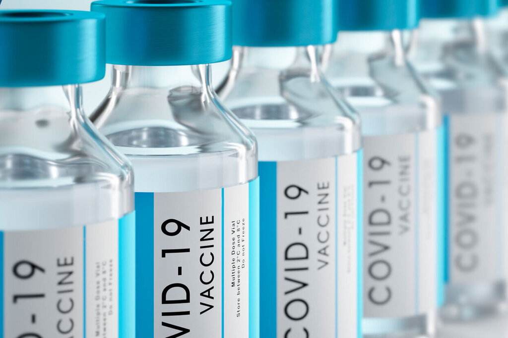 Row of vaccine vials with blue caps, labeled 'COVID-19 Vaccine.