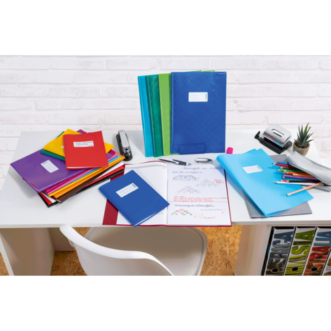 Ein Schreibtisch mit bunten Ordnern, Notizheften, Stiften und Bürobedarf, umgeben von einem minimalistischen, hellen Hintergrund.