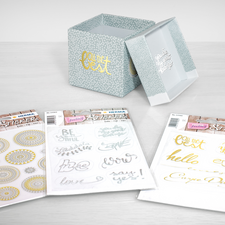 Dekorative Aufbewahrungsbox mit einem Deckel, umgeben von drei Packungen mit Aufklebern in verschiedenen Designs und Schriftzügen.