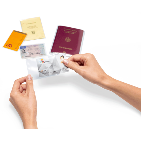 Eine Hand hält eine transparente Hülle mit einer ID-Karte, umgeben von einem Reisepass und mehreren anderen Ausweisen.