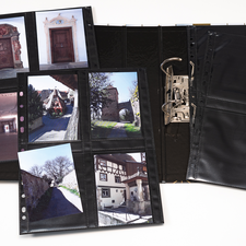 Ein Fotoalbum mit mehreren Seiten, die Bilder von historischen Gebäuden und Straßen zeigen, liegt geöffnet auf einem Tisch.