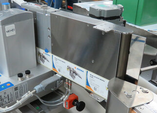A labeling machine with multiple label rolls and control elements, designed for industrial applications.