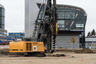 Construction equipment of the type Liebherr LB 24 at a construction site, surrounded by modern buildings and construction markings.