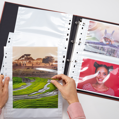 Eine Person hält ein Foto von einer Landschaft mit Reisfeldern, während ein Fotoalbum mit weiteren Bildern geöffnet ist.