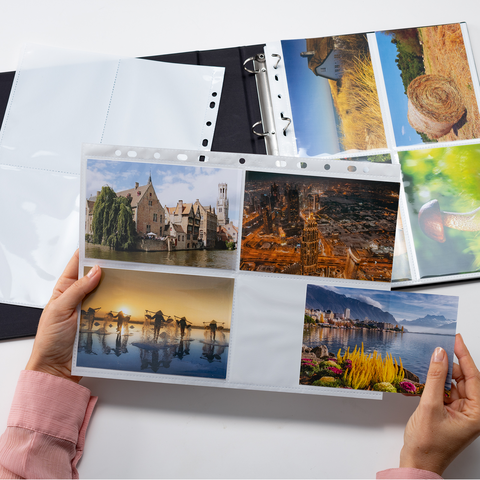 Eine Person hält ein Fotoalbum mit mehreren Bildern von Landschaften, Gebäuden und Naturmotiven in der Hand.