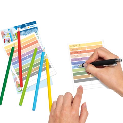 Bunte Stifte liegen neben einem Blatt, auf dem mit einem Stift geschrieben wird. Farbkarten sind ebenfalls sichtbar.