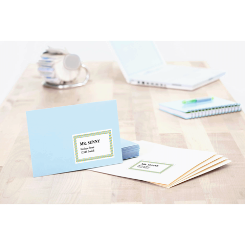 Blaue Karte mit dem Namen "Mr. Sunny" und der Aufschrift "Tischkarten" auf einem Holztisch, umgeben von weiteren Briefen und Büromaterial.