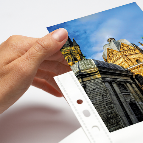 Eine Hand hält ein Foto eines historischen Gebäudes mit Türmen und einem blauen Himmel im Hintergrund.