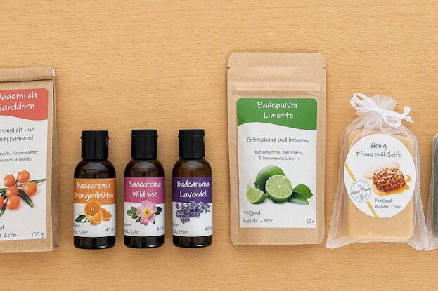 Custom labels for cosmetic products in a range: plant oil soaps in clear bags, doypacks with bath milk and bath powder, as well as brown glass bottles with bath aroma, displayed on a light wooden surface.