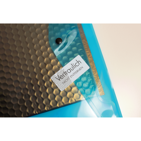 Transparente Hülle mit einem schwarzen, gewellten Innenmaterial und einem Aufkleber, der "Vertraulich" und "Entfernen" zeigt.