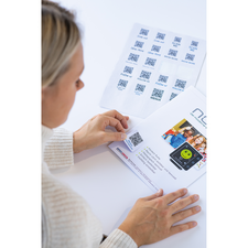 Eine Person scannt einen QR-Code auf einem Menüblatt, während ein weiteres Blatt mit mehreren QR-Codes im Hintergrund liegt.