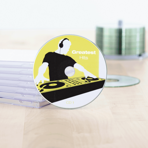 CD mit dem Titel "Greatest Hits", zeigt einen DJ mit Kopfhörern und einem Plattenteller-Design. Im Hintergrund sind CD-Hüllen sichtbar.