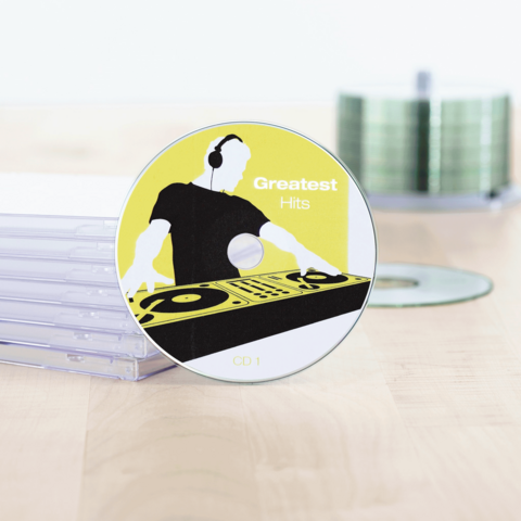 CD mit dem Titel "Greatest Hits", zeigt einen DJ mit Kopfhörern und einem Plattenteller-Design. Im Hintergrund sind CD-Hüllen sichtbar.