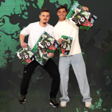 Zwei Männer halten jeweils ein Plakat mit einem Fußballmotiv in den Händen und posieren vor einem bunten, grafischen Hintergrund.