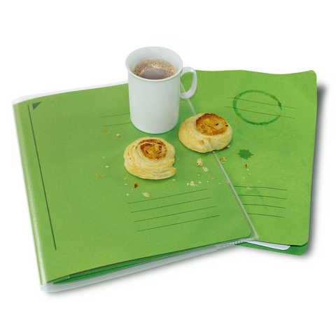 Grüne Ordner liegen auf einem Tisch, daneben eine Tasse mit Getränk und zwei Gebäckstücken.