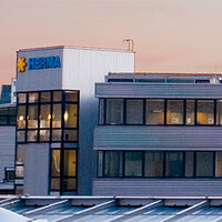 The building with the HERMA logo, several windows, and modern architecture, set against a gentle evening sky.