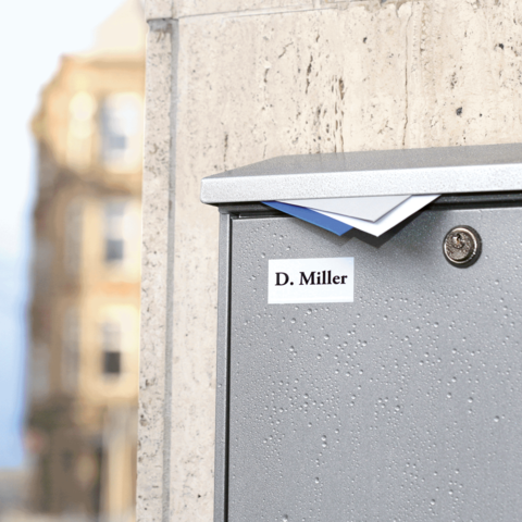 Briefkasten mit dem Namen "D. Miller" auf einer Wand, leicht feucht von Regen.