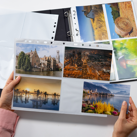 Eine Person hält ein Fotoalbum mit mehreren Bildern von Landschaften, Gebäuden und Natur. Einige Seiten sind leer.