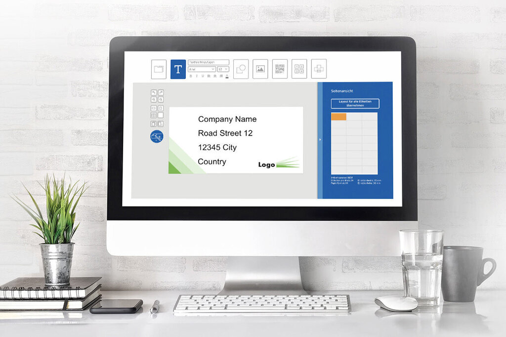 A computer screen displays a presentation with text and graphics. On the table, there are plants, notepads, and a glass of water.
