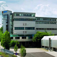 Modern office buildings with glass facades and greenery in the foreground.