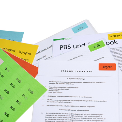 Several documents with colorful sticky notes, including a production contract and notes on PBS and Facebook.