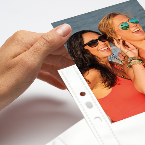 Two women wearing sunglasses smile and pose happily for a photo. One woman has long, curly hair, while the other has a blonde hairstyle.