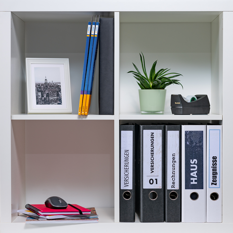 Shelf with file folders, a plant, a picture frame, and writing supplies. Folders labeled 'INSURANCE', 'BILLS', 'HOUSE', and 'CERTIFICATES'.