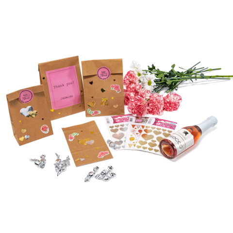 Geschenktüten mit Aufklebern, ein Blumenstrauß, Herzaufkleber und eine Flasche Roséwein liegen auf einem Tisch.
