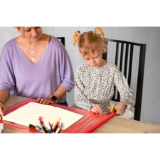 Eine Frau und ein kleines Mädchen sitzen an einem Tisch, während sie an einem leeren Notizbuch arbeiten. Buntstifte sind sichtbar.