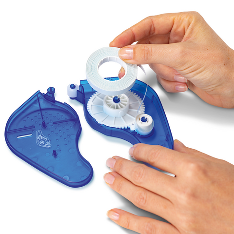 A hand holds a roll of tape above a blue tape dispenser that is partially open, revealing its mechanism.