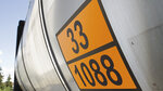 A silver tank with orange stickers displaying the numbers 33 and 1088 stands against a clear sky.