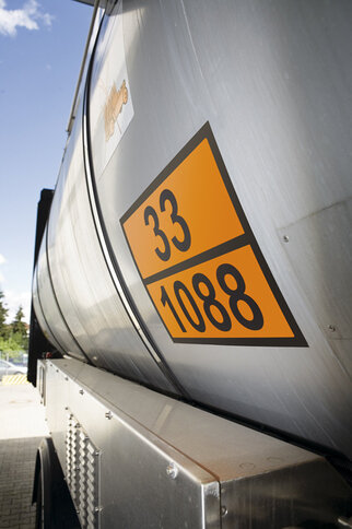 A silver tank with orange stickers displaying the numbers 33 and 1088 stands against a clear sky.