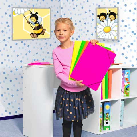 Ein Mädchen hält bunte Bastelpapierblätter in der Hand, steht in einem Raum mit bienen- und blumenförmigen Bildern an der Wand.