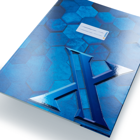 Blaues Heft mit hexagonalem Muster und hervorgehobenem, glänzendem "X" auf der Vorderseite. Ein Etikett mit Platz für eine Beschriftung ist sichtbar.