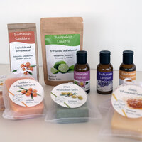 Labels on various cosmetic products: Doypacks with bath milk and bath powder, brown glass bottles with bath aroma, and plant oil soaps with round labels in clear bags, set against a light background.