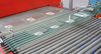 Glass plates are transported on a conveyor belt, clearly visible with several labels for identification.