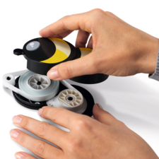 One hand holds a yellow and black dispenser, while another hand pulls out the string.