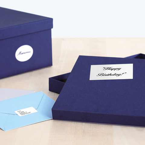 Eine geöffnete, dunkelblaue Geschenkbox mit der Aufschrift "Happy Birthday!" und zwei Umschlägen in verschiedenen Farben.