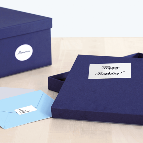 Eine geöffnete, dunkelblaue Geschenkbox mit der Aufschrift "Happy Birthday!" und zwei Umschlägen in verschiedenen Farben.