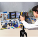 Eine Person fotografiert eine Vielzahl von Büro- und Bastelmaterialien, darunter Ordner, Kleber und kreative Werkzeuge, auf einem Tisch.