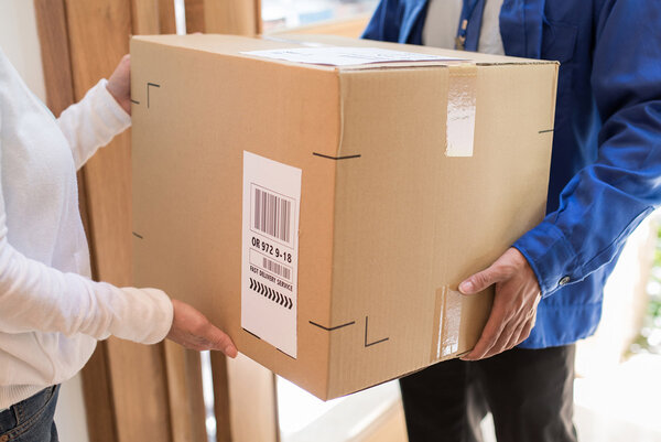 Shipping and pallet labels: Package delivery at the front door, man hands over package with shipping label.